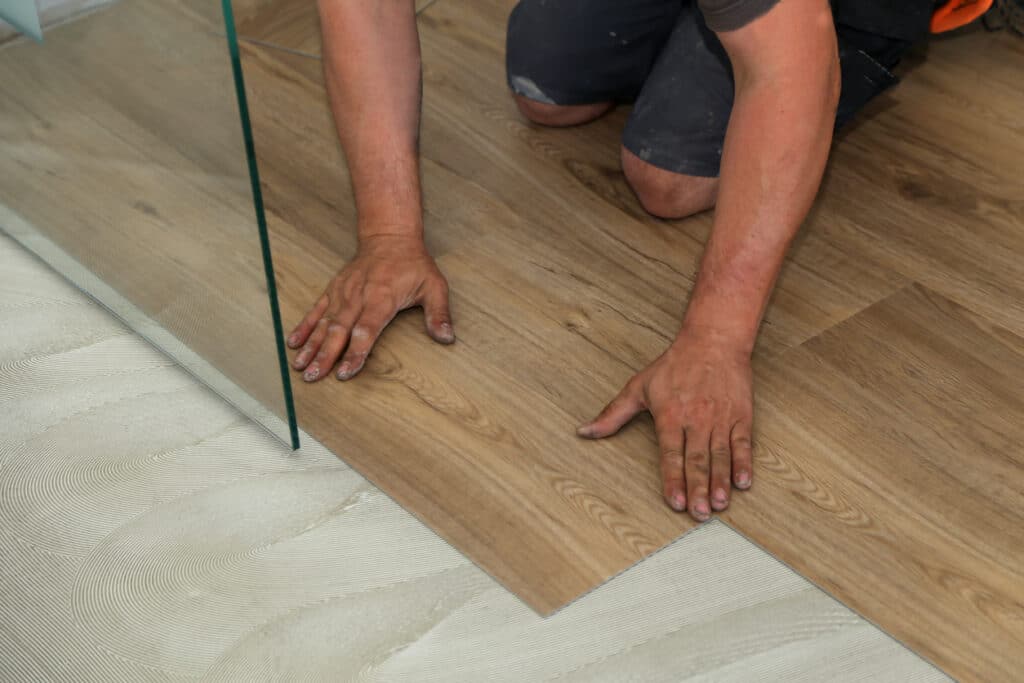 Flooring contractor on hands and knees installing LVT flooring